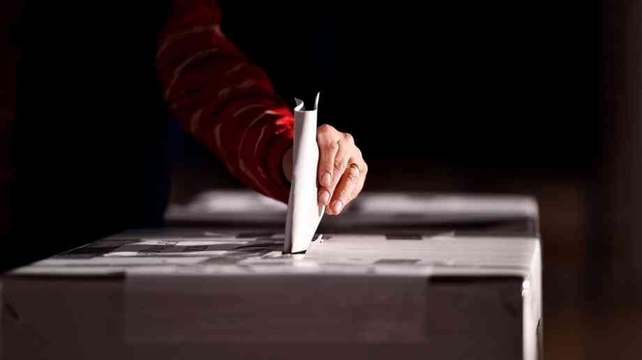 Hand casting a vote into the ballot box
