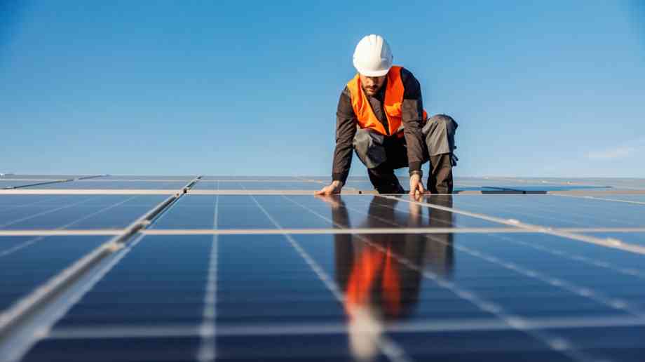 Construction worker installs solar panels on rooftop