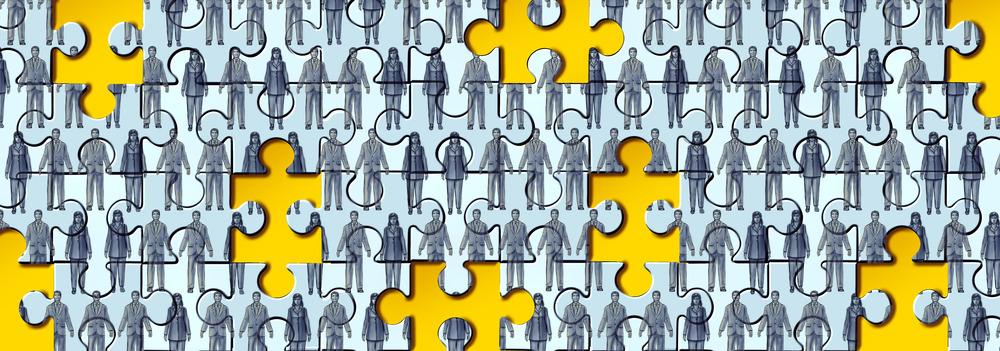 A jigsaw set with some pieces missing. The jigsaw is of lots of people in black and white holding hands. The blank spaces are coloured yellow.